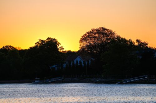 Free Tranquil sunset scene with silhouetted trees and calm water, evoking peace. Stock Photo