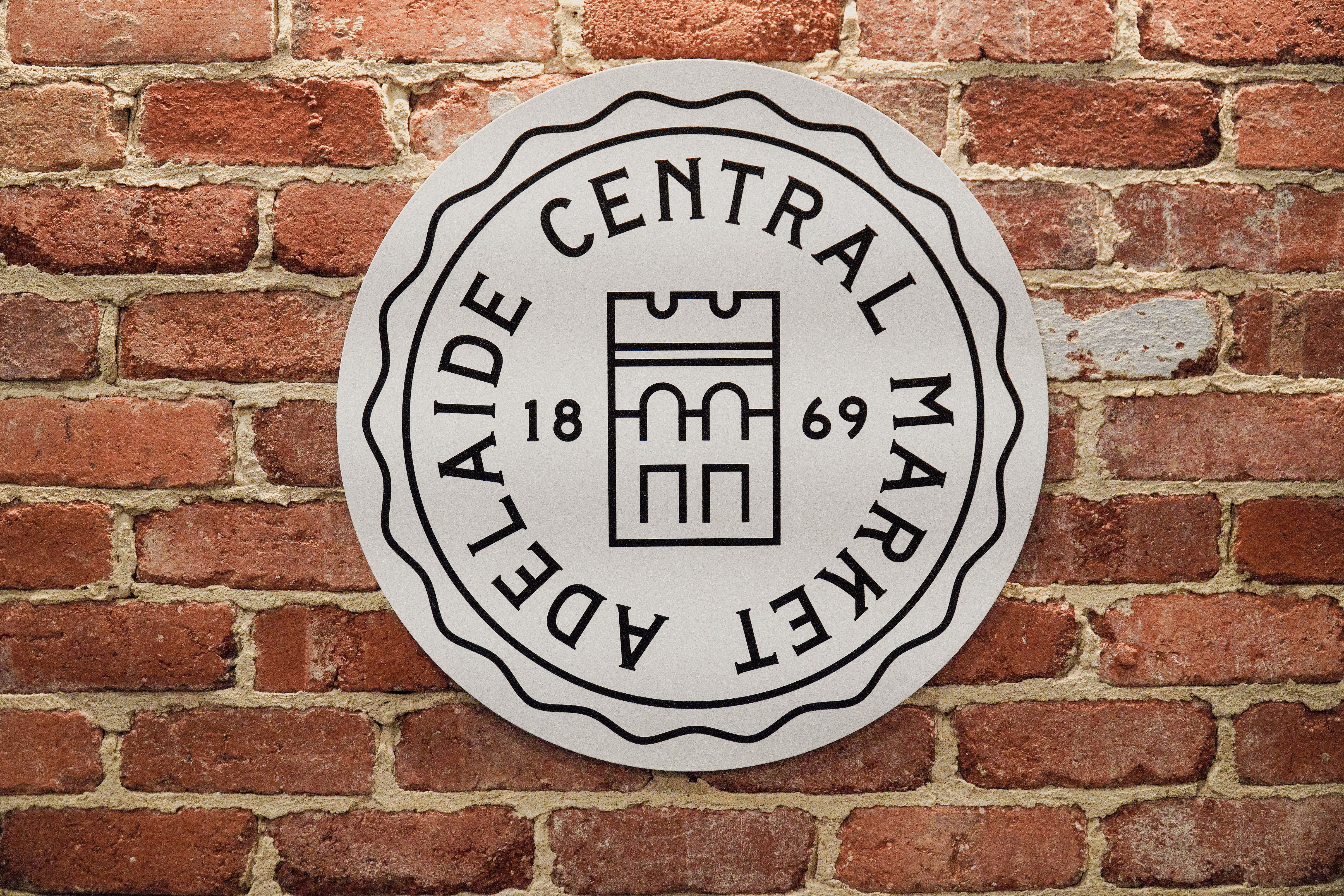 Historic Adelaide Central Market sign displayed against a rustic brick wall.