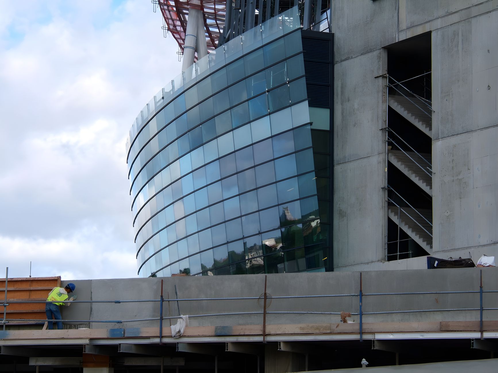 View of ongoing construction work at Emirates Stadium in London, featuring modern glass architecture.