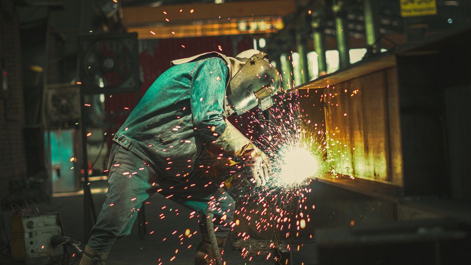 Shipyard workers welding structural steel on a large hull section