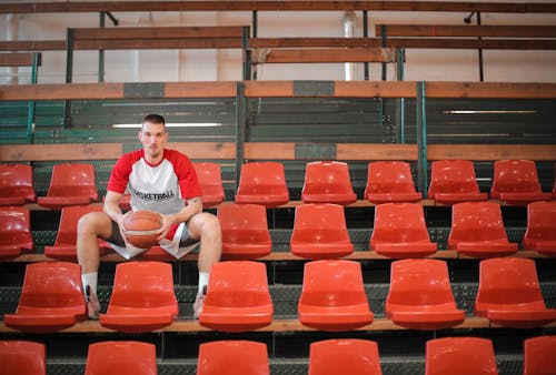 Tall basketball player with ball on sports seat