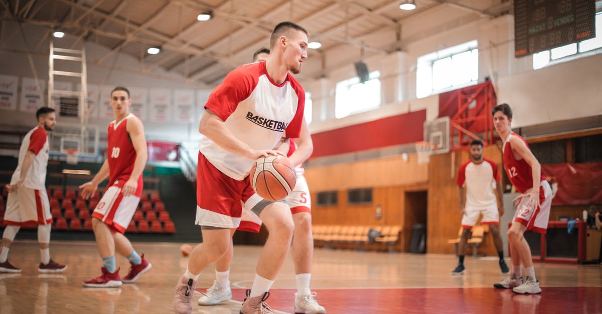 basketball player practicing a hesitation dribble in a gym, focus on footwork