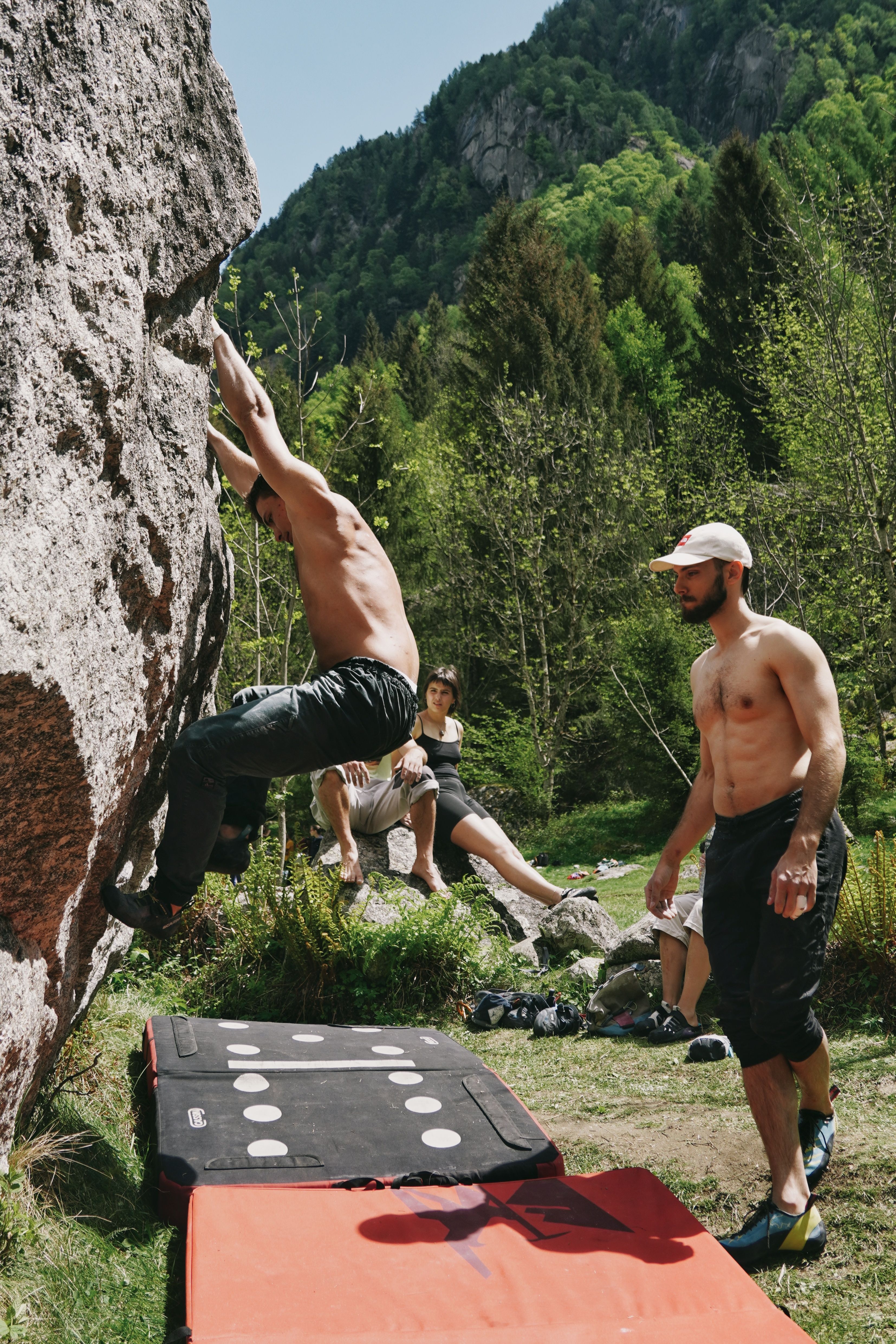 Group of climbers enjoying outdoor rock climbing on a sunny day with lush green backdrop.