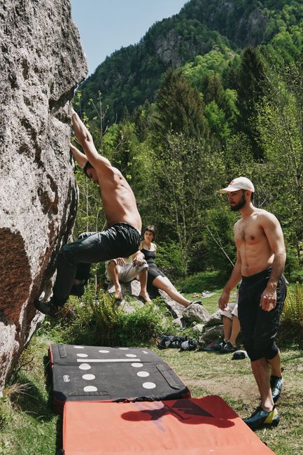 Group of climbers enjoying outdoor rock climbing on a sunny day with lush green backdrop.