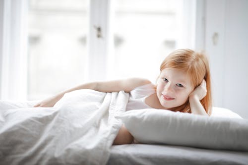 Free Girl Lying on White Bed Stock Photo