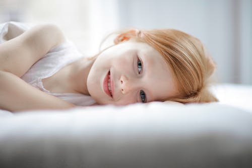 Free Girl in White Tank Top Lying on Bed Stock Photo