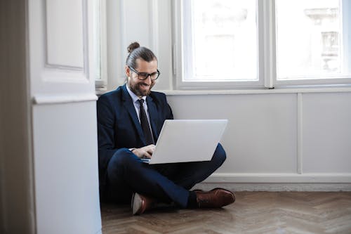 Man in Navy Blue Suit Jacket Sitting Down Using Macbook