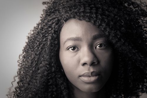 Free Close-up black and white portrait of a young woman with curly hair showcasing a serene expression. Stock Photo