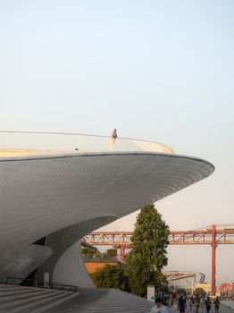 Elegant view of MAAT Museum in Lisbon, featuring modern architecture against a sunset sky.