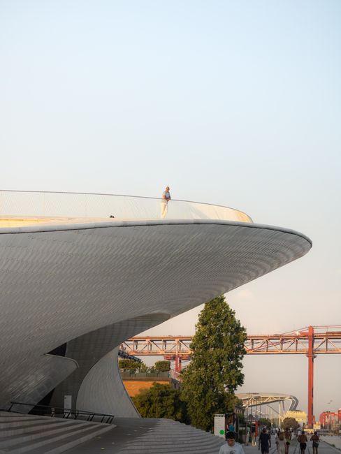 Elegant view of MAAT Museum in Lisbon, featuring modern architecture against a sunset sky.