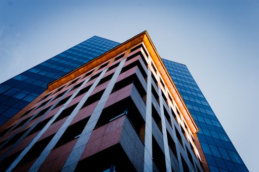 Dramatic angular view of a modern skyscraper in Warsaw, reflecting the blue sky at dusk.
