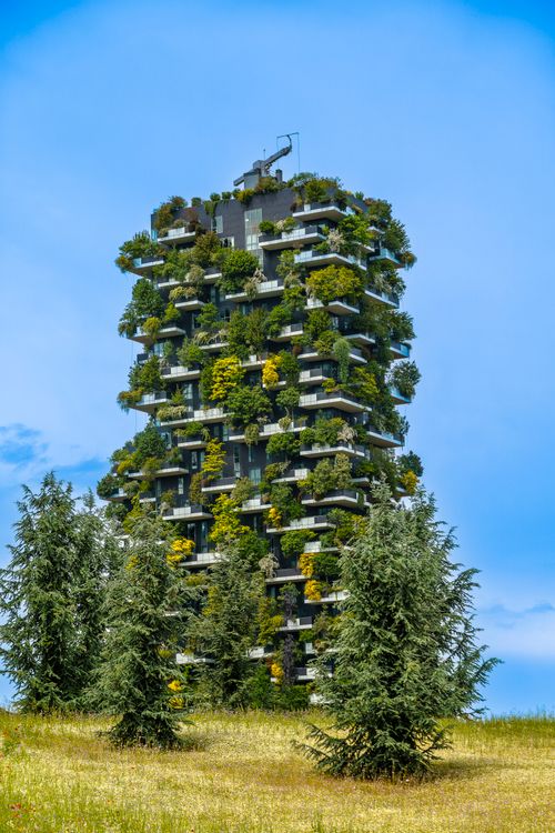 Free Stunning vertical forest building in Milan set against a bright blue sky. Stock Photo