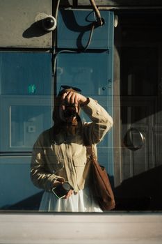 A creative reflection of a photographer in a glass window, capturing an urban street scene.