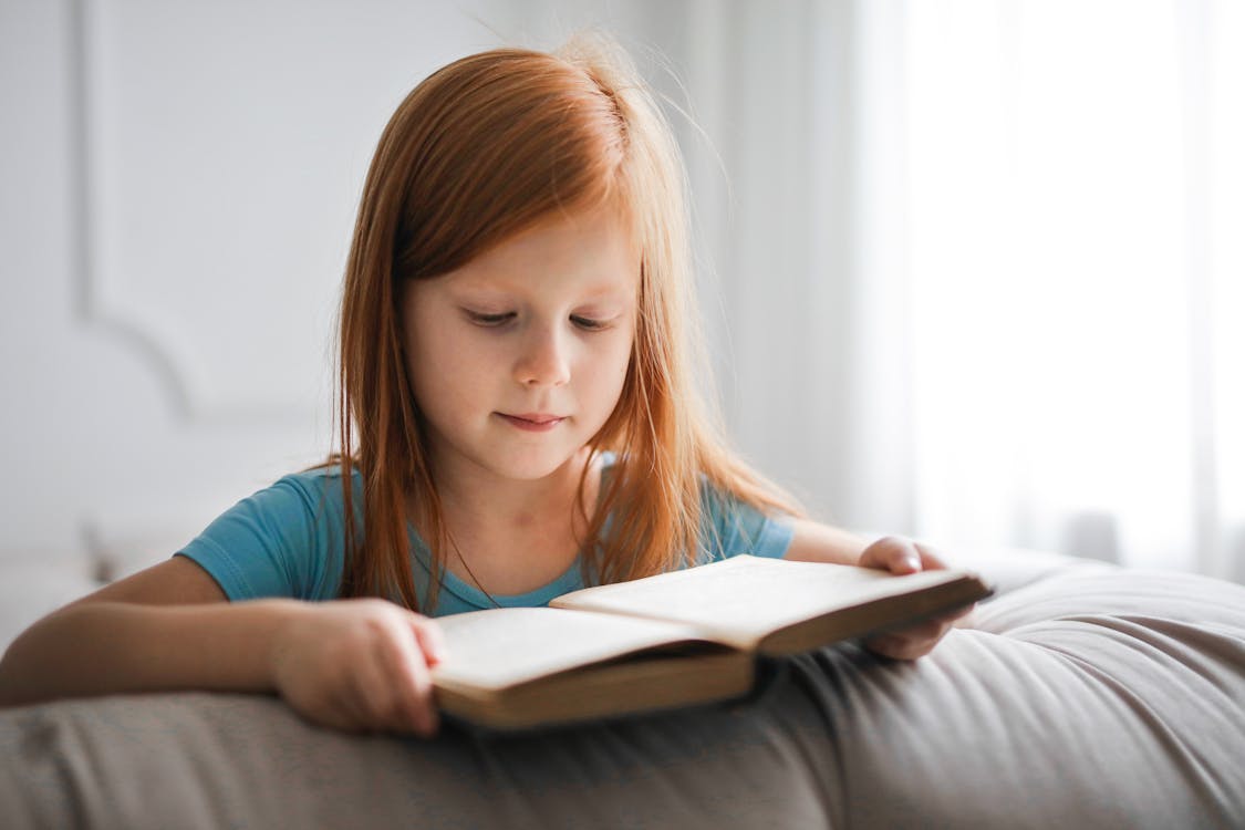 Free Girl in Blue T-shirt Reading Book Stock Photo