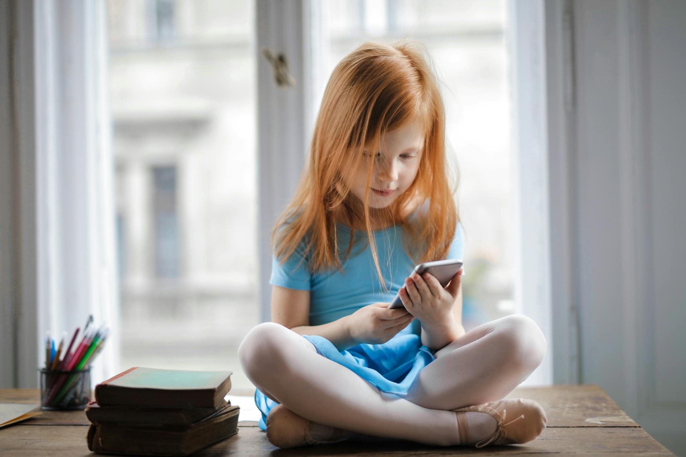 Child with phone Photo by Andrea Piacquadio from Pexels: https://www.pexels.com/photo/calm-small-ginger-girl-sitting-on-table-and-using-smartphone-in-light-living-room-3755620/