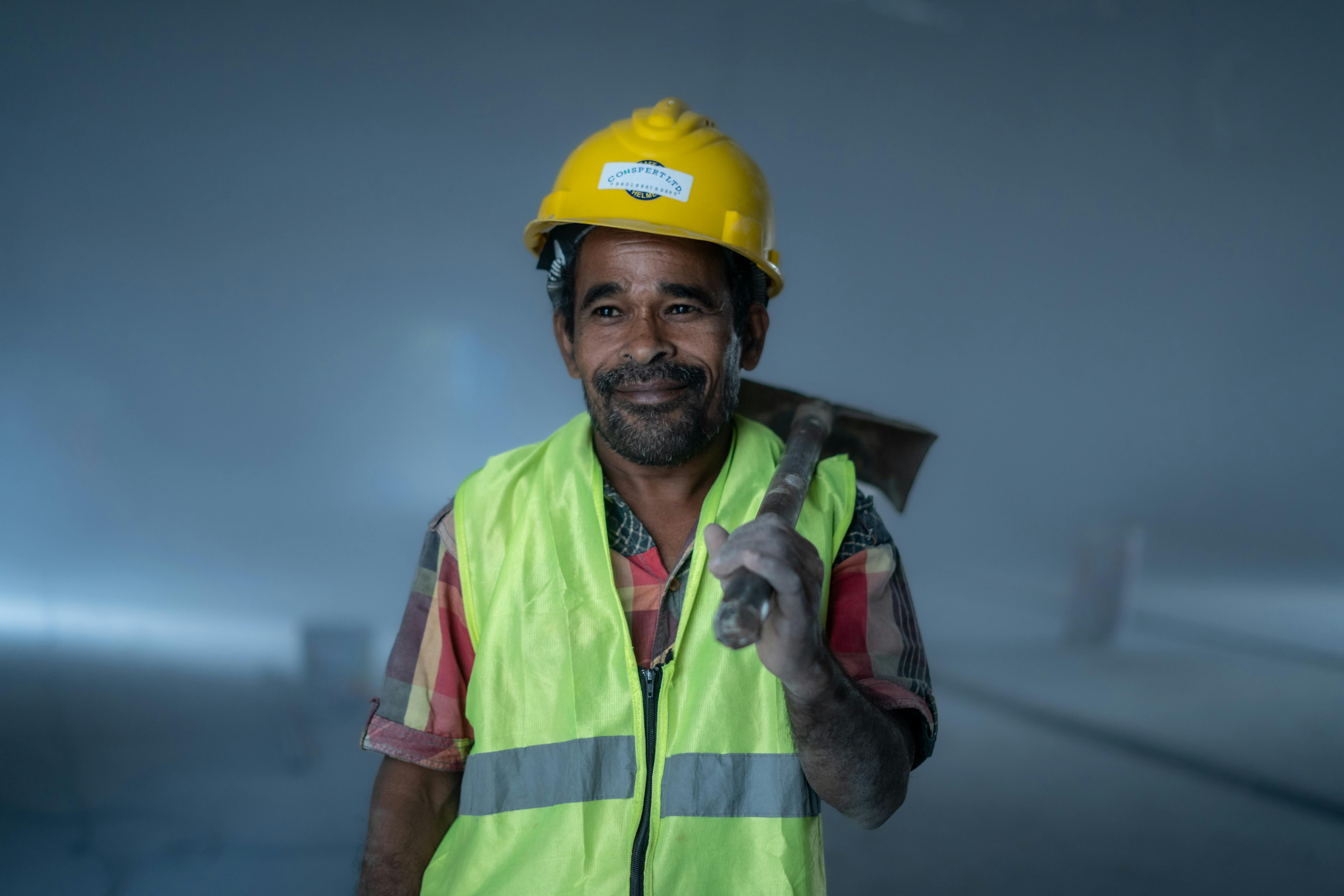 Ouvrier du bâtiment souriant, en tenue de sécurité, tenant un outil à l'intérieur. Thème professionnel et industriel.