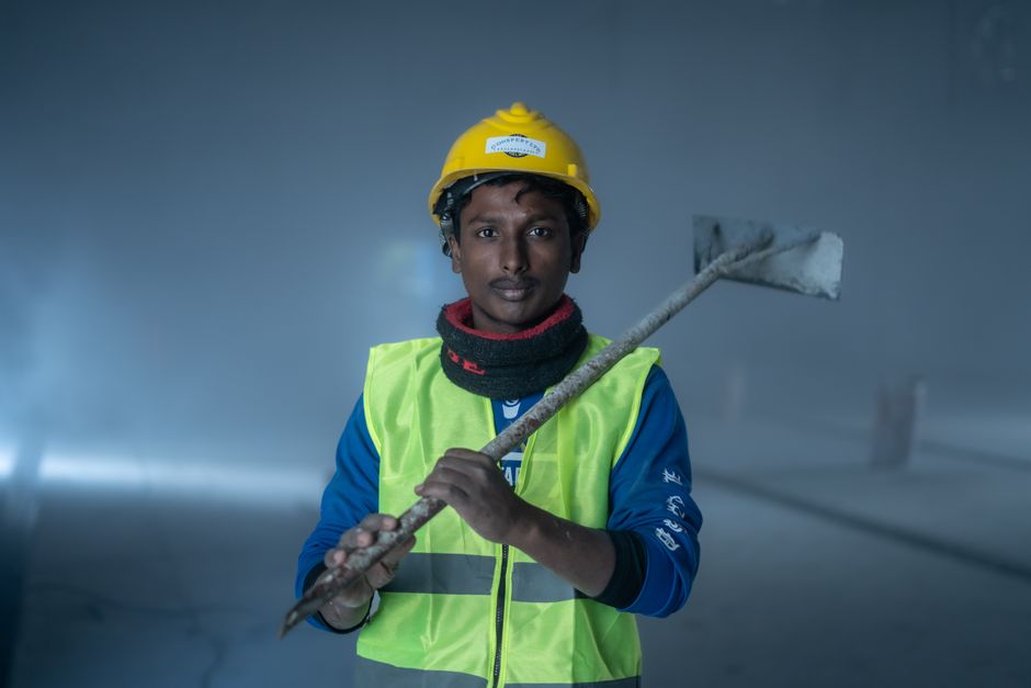 Portrait of a construction worker indoors with safety gear, showcasing a confident pose.