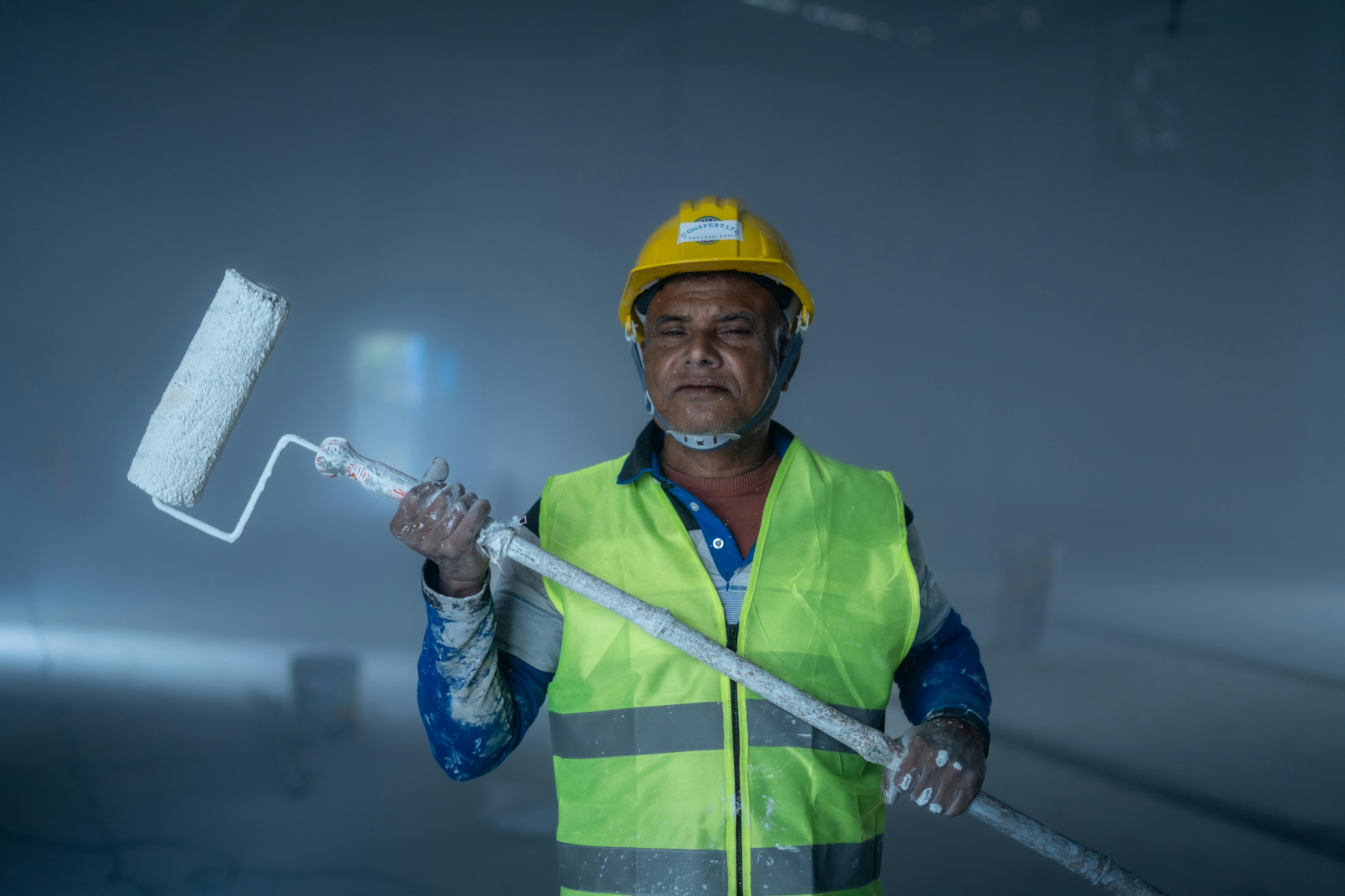 Commercial painter with roller and safety equipment on a large building project