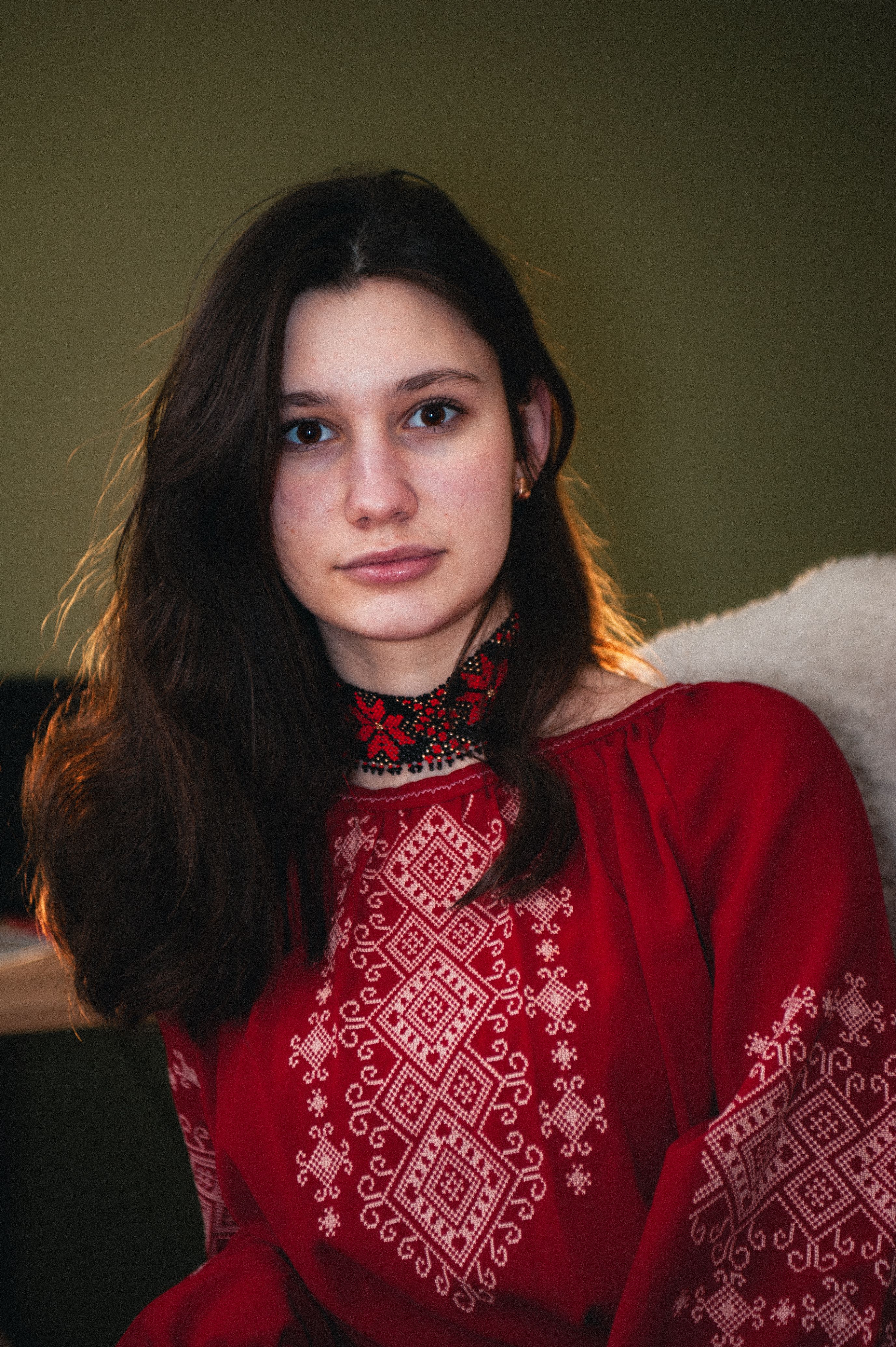 Portrait of a Ukrainian woman in traditional red attire, showcasing cultural embroidery.