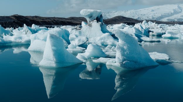 Stunning icebergs reflect in the serene waters of Jökulsárlón, Iceland's iconic glacial lagoon.