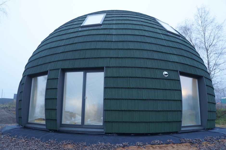 Unique green dome house on a foggy day, showcasing contemporary architecture.