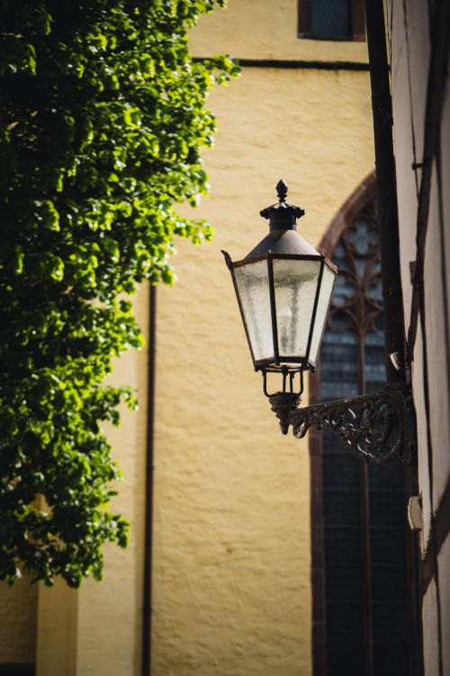Free Charming historic street lamp on an ornate bracket against an old building with lush foliage. Stock Photo