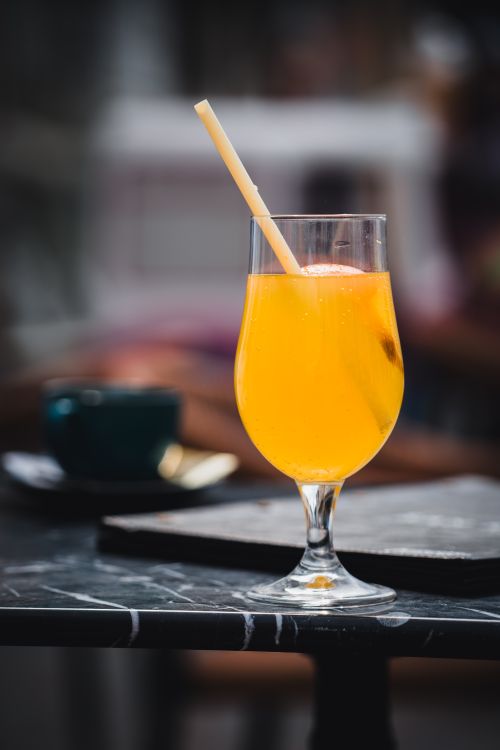 Free A vibrant glass of orange juice with a straw on a café table in Lemgo, Germany. Stock Photo