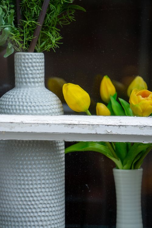 Free Charming display of yellow tulips and textured vases in a window setting, evoking spring vibes. Stock Photo