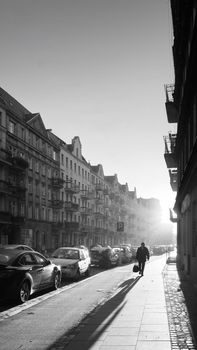 Moody monochromatic street scene in Wrocław with long shadows and architectural details.