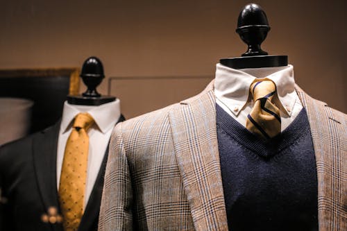 Dandy fancy jackets with shiny ties on dummies in showroom of contemporary male shop