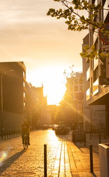 A serene street scene at sunset featuring a cyclist in silhouette, capturing urban tranquility.