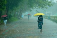 People walking under umbrellas on a rainy day in a park. Vivid colors and lush greenery.