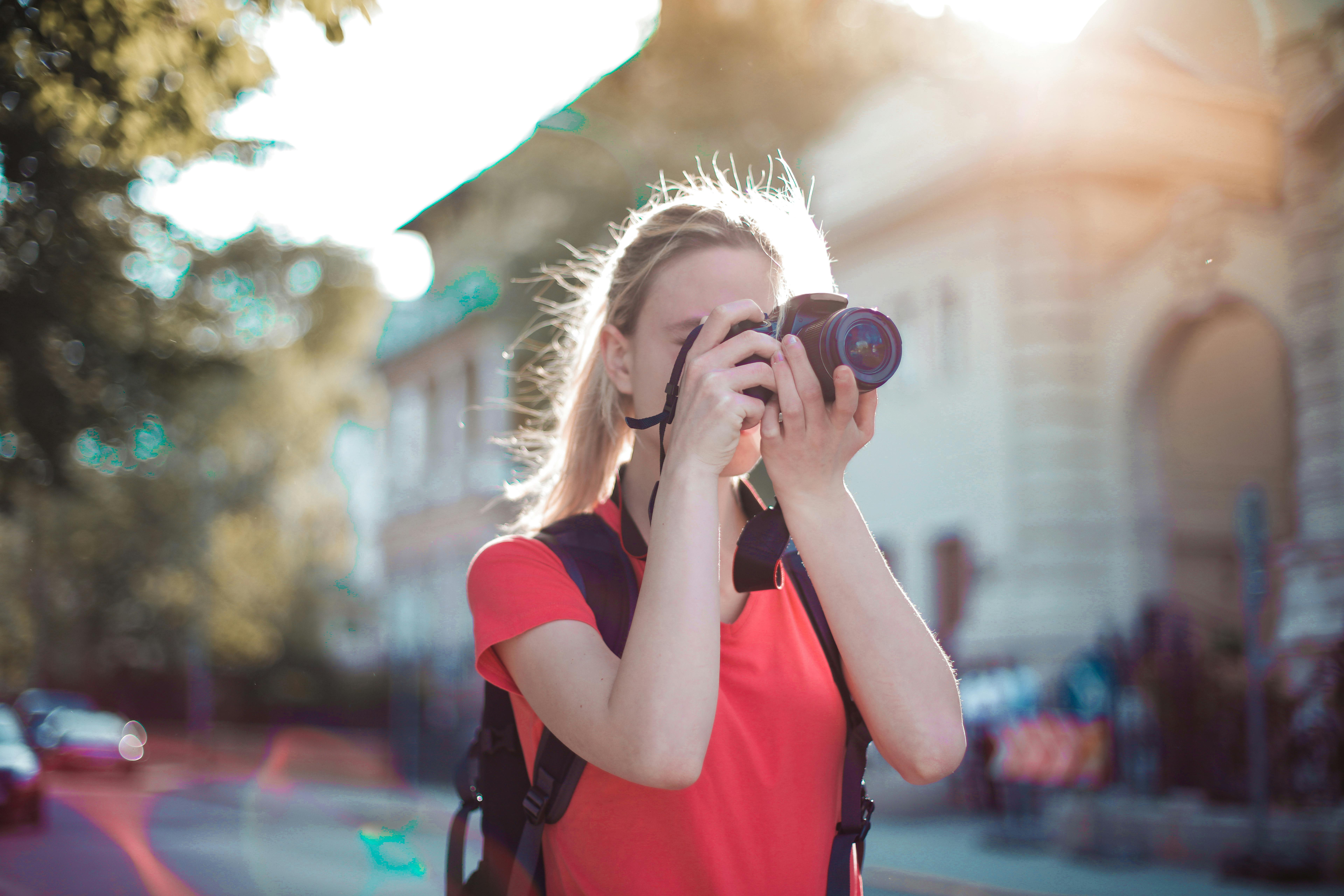 woman in red shirt taking pictures using dslr camera