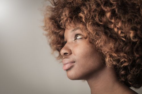 Free Close-up of a young woman with curly hair looking pensive in a studio setting. Stock Photo