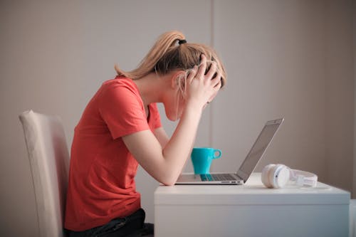 Free Woman in Red T-shirt Looking at Her Laptop Stock Photo