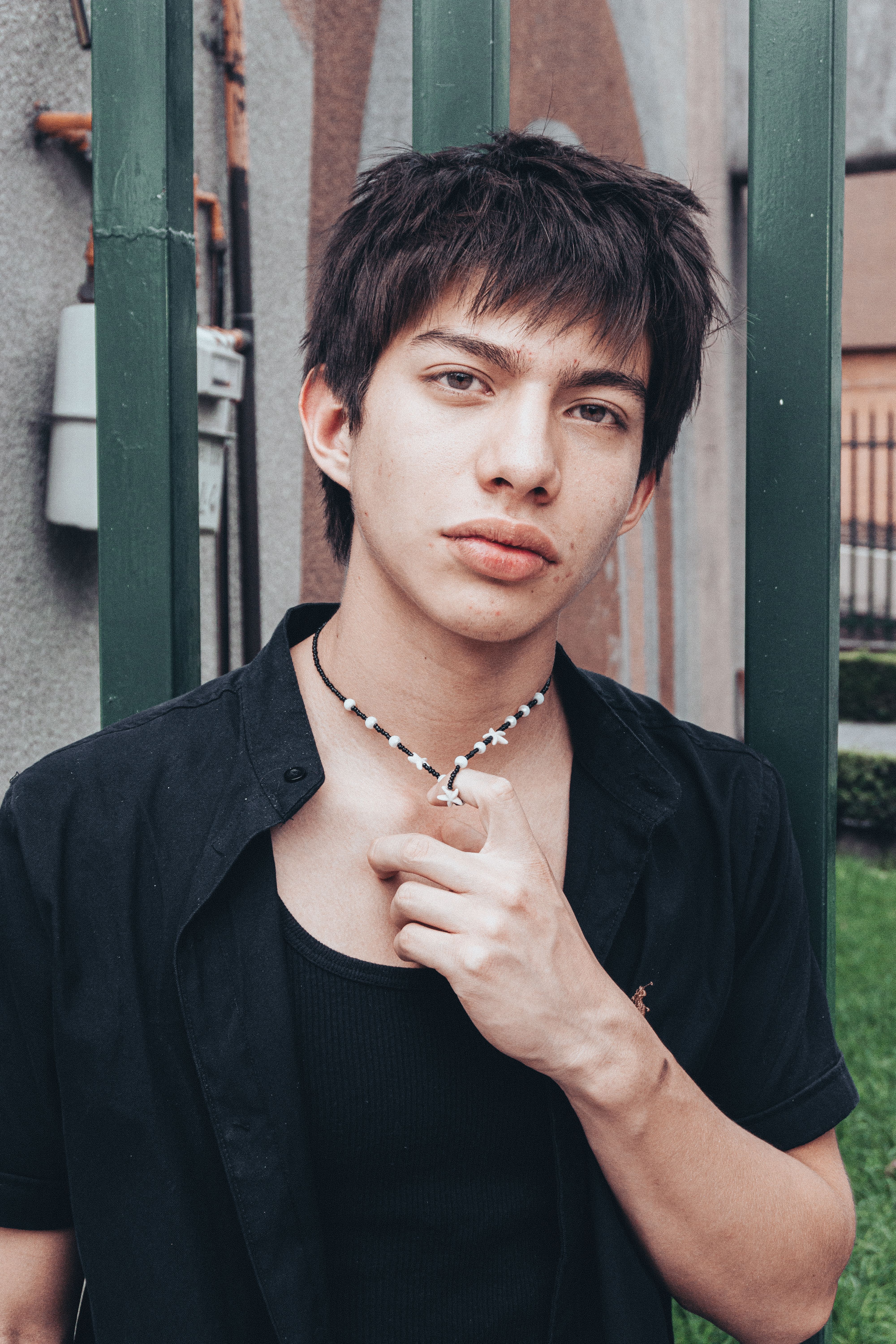 Portrait of a young man standing casually outdoors, showcasing style and attitude.