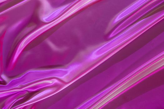 A close-up of shimmering iridescent pink fabric with gentle folds, creating a luxurious texture.