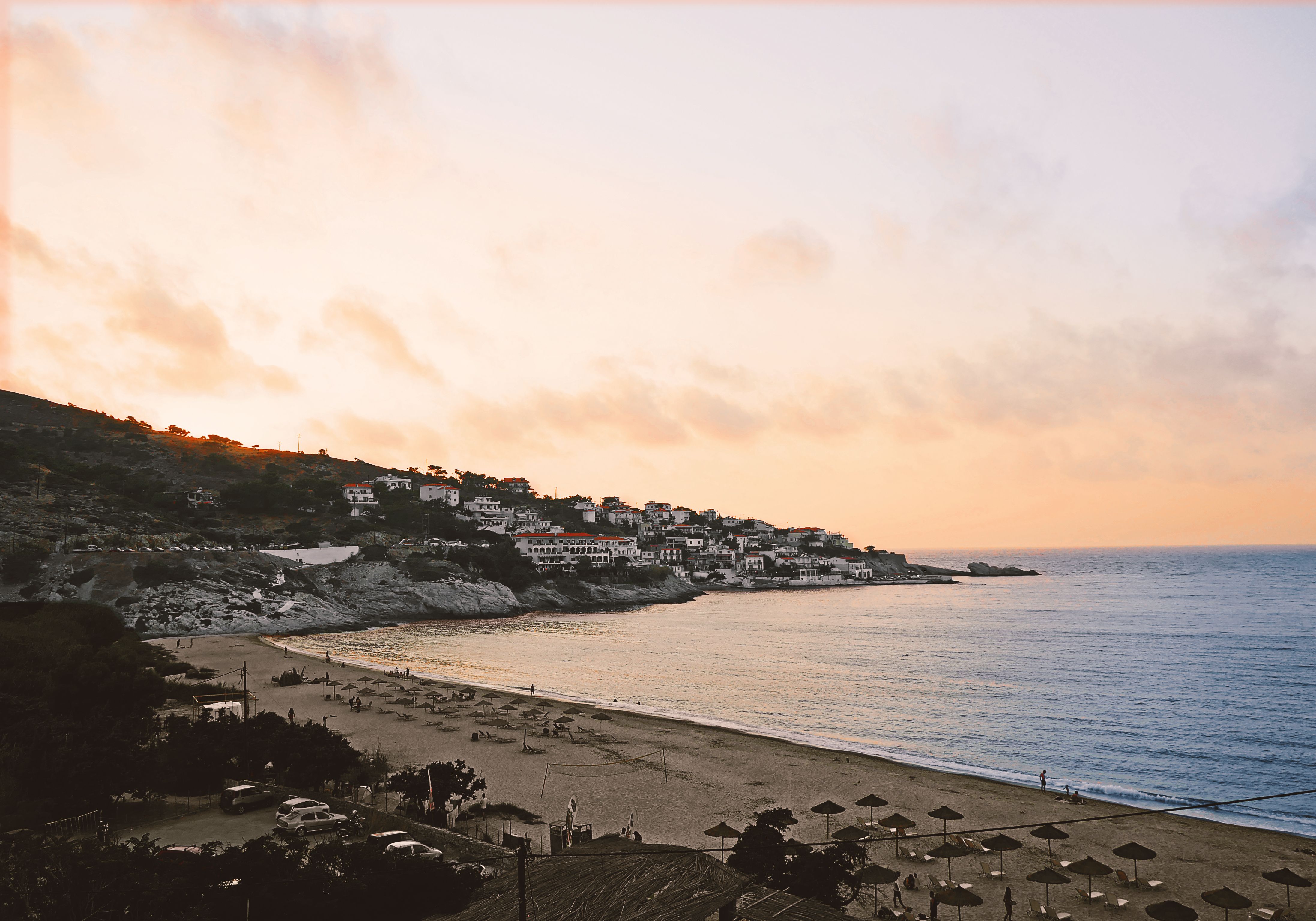 Gorgeous sunset view of a beach and coastal village in Ikaria, Greece, during the blue hour.