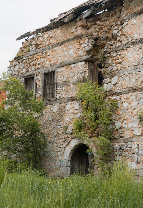 Free An old and dilapidated stone house with overgrown vegetation, presenting a rustic and historical charm. Stock Photo