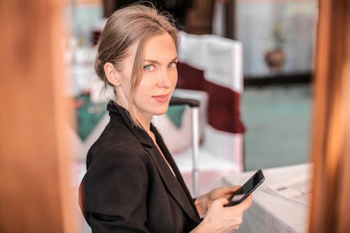 Woman in Black Coat Holding Black Smartphone