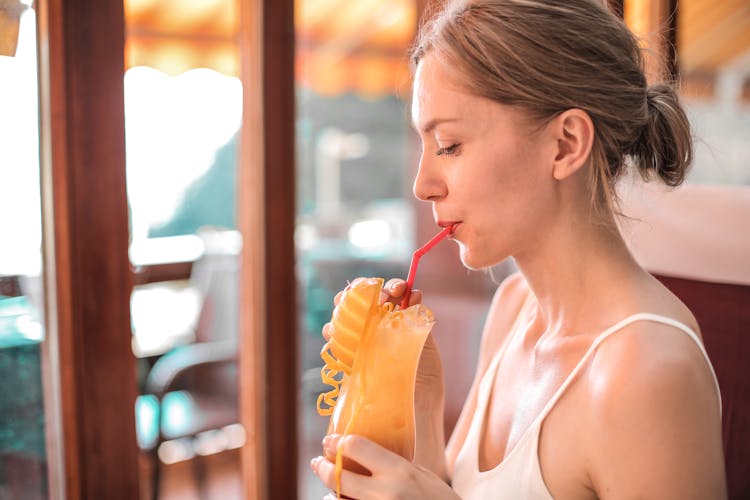 Woman In White Tank Top Drinking Orange Juice