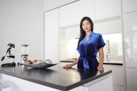 An attractive woman poses in a stylish, contemporary kitchen with sleek design elements.