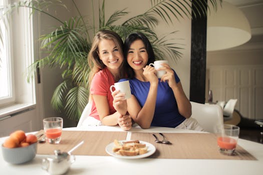 两个女人在室内微笑着喝咖啡，享受团聚的时光，呈现出一幅友谊休闲的场景
