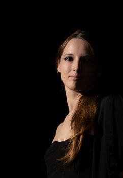 Elegant portrait of a woman in dramatic studio lighting with a dark background.