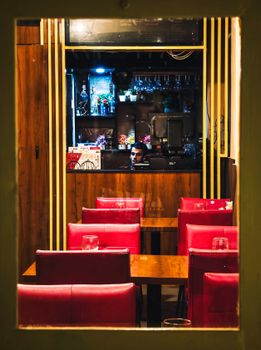 Warm interior view of a cozy restaurant with red seating and bar decoration.