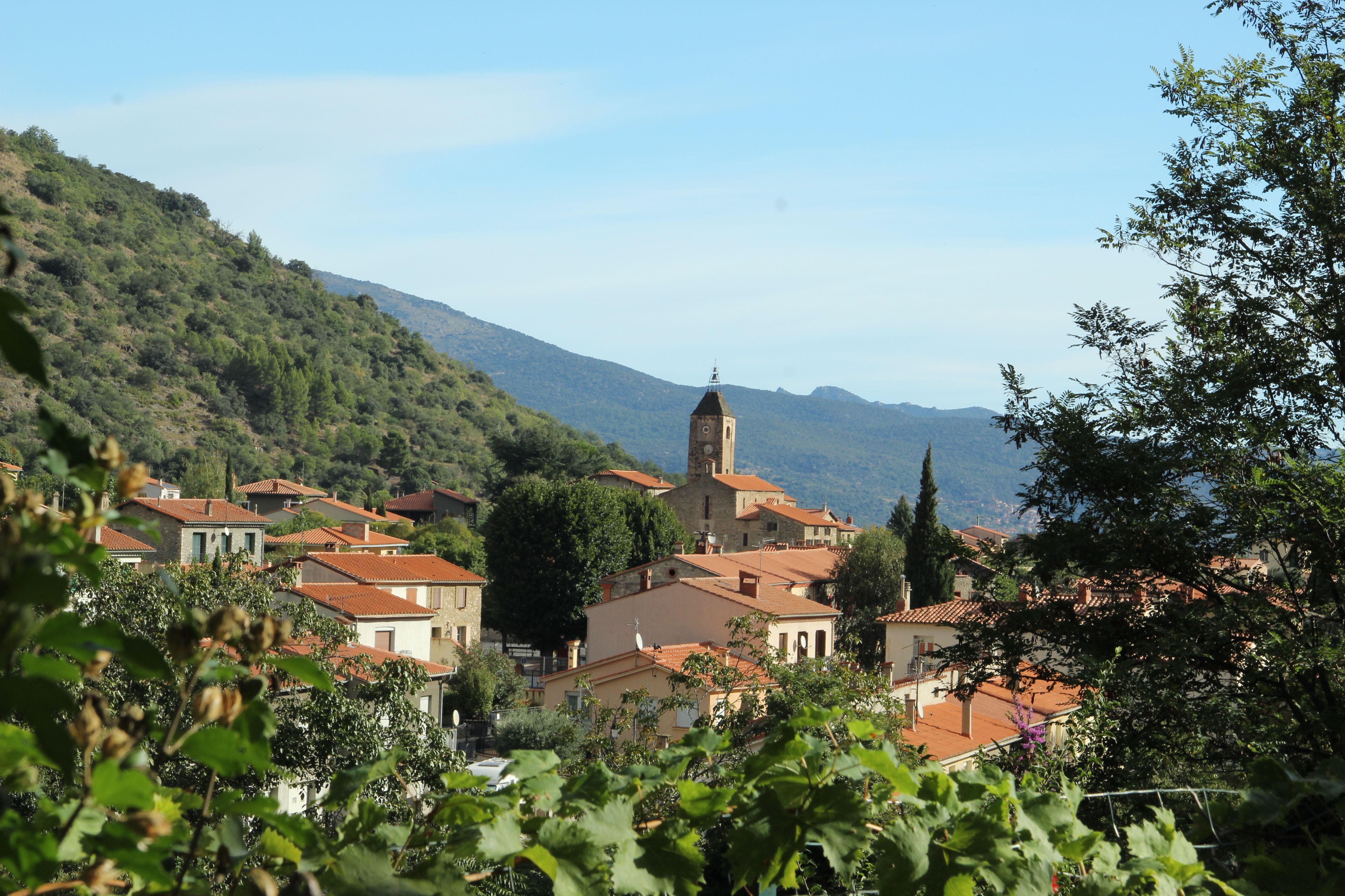 Picturesque village with terracotta rooftops and church tower nestled in lush greenery.
