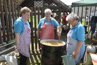 Three women prepare a traditional dish outdoors in Győrtelek, Hungary, showcasing cultural cooking techniques.