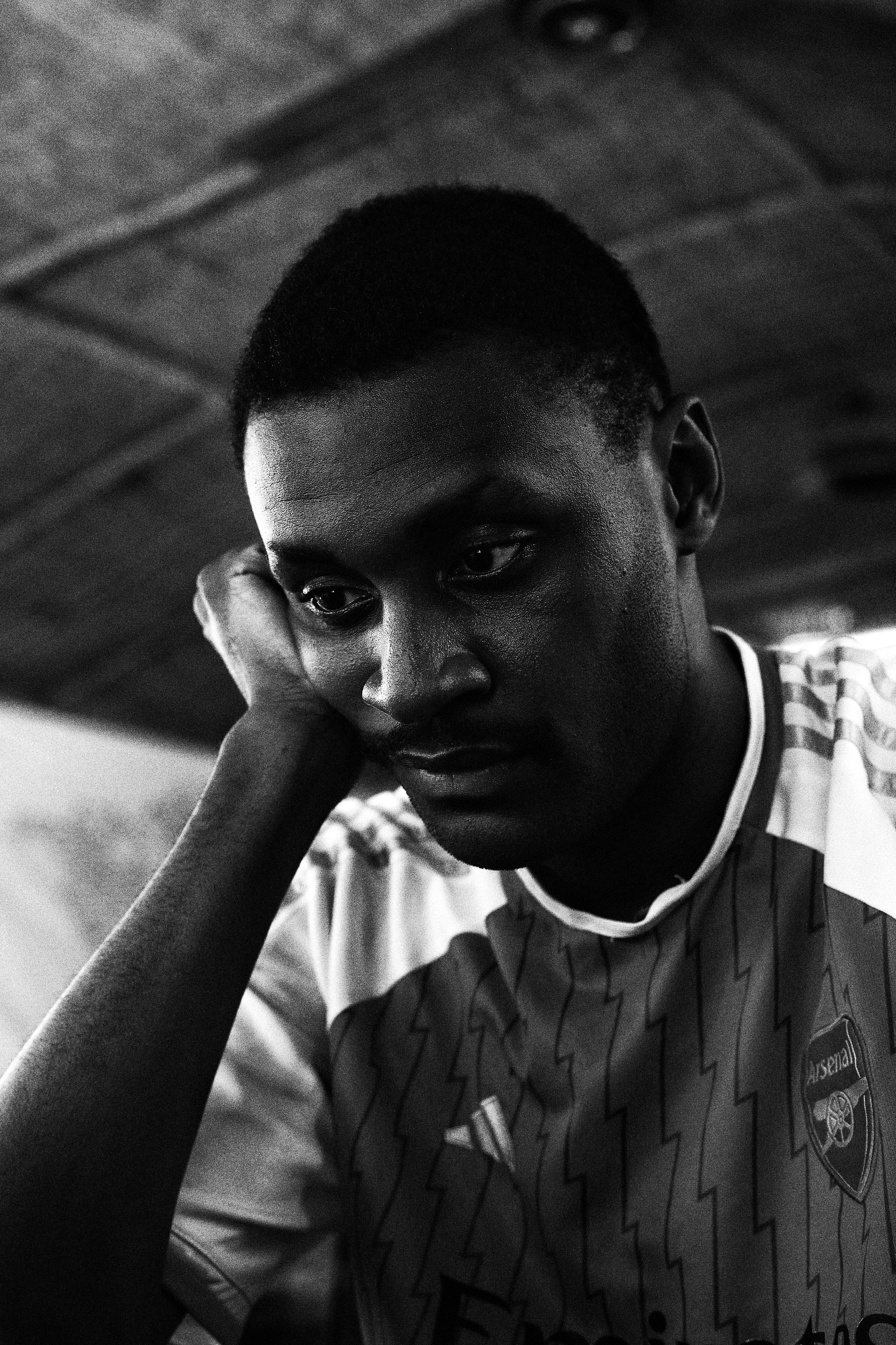 Black and white close-up portrait of a thoughtful young man indoors.
