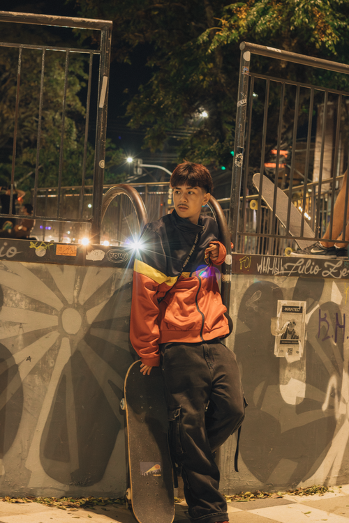 Free Young skateboarder leaning against rail at night in urban setting. Stock Photo