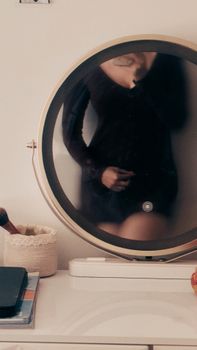 Artistic reflection of a woman in a circular mirror on a desk, indoor setting.
